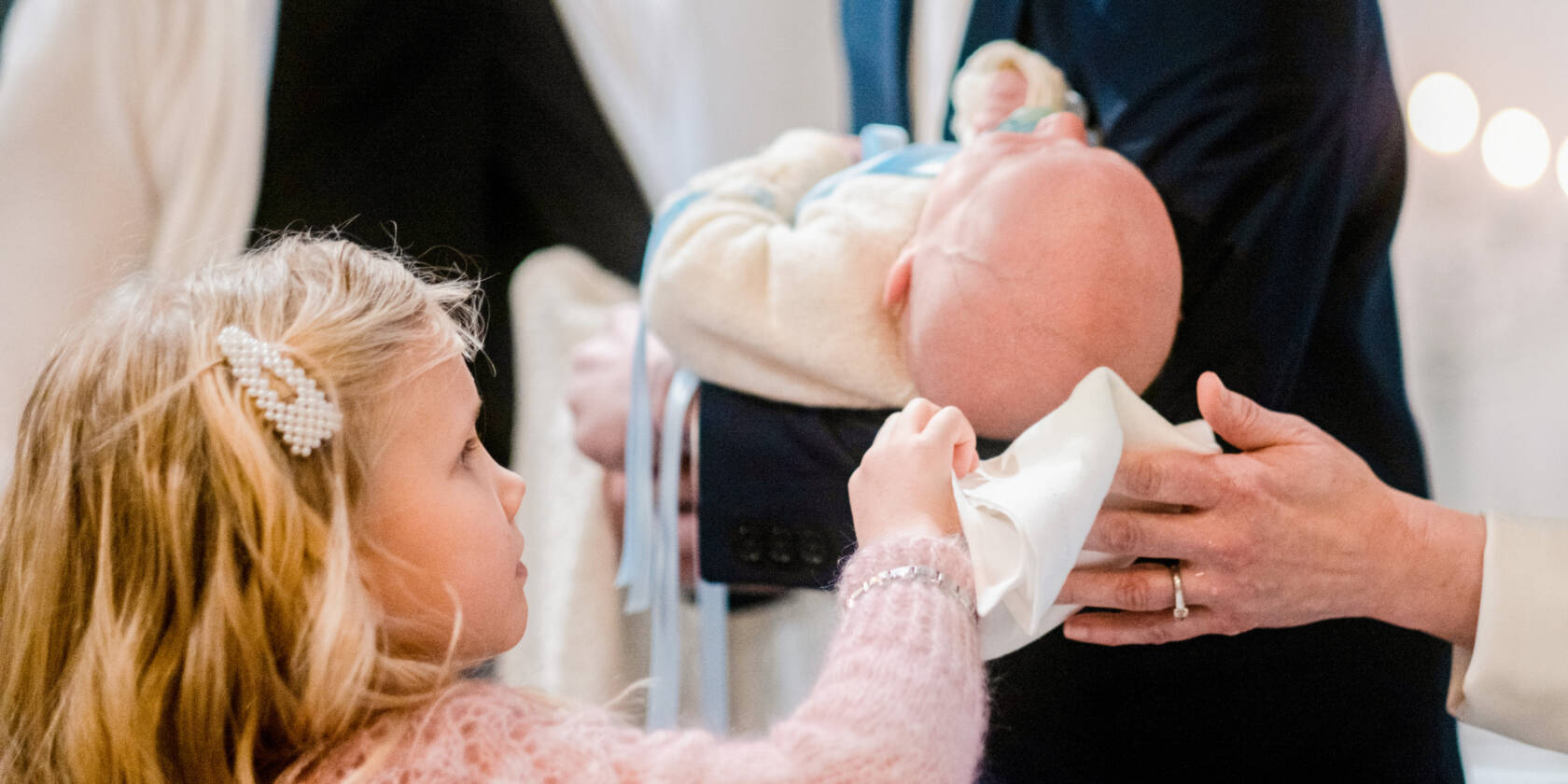 Isosisko kuivaa vauvan päätä kastetoimituksessa.