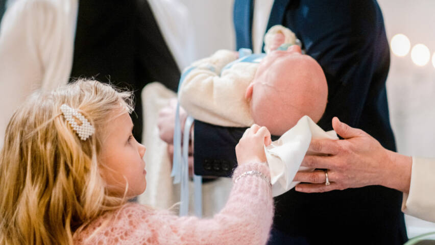Isosisko kuivaa vauvan päätä kastetoimituksessa.