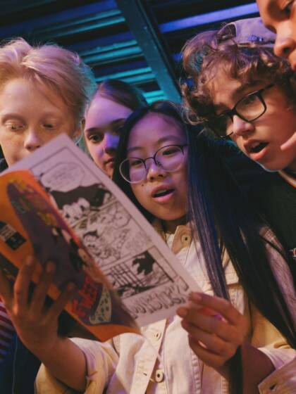 Several young people are looking at a magazine.
