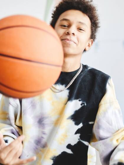 A boy is playing with a basket ball.