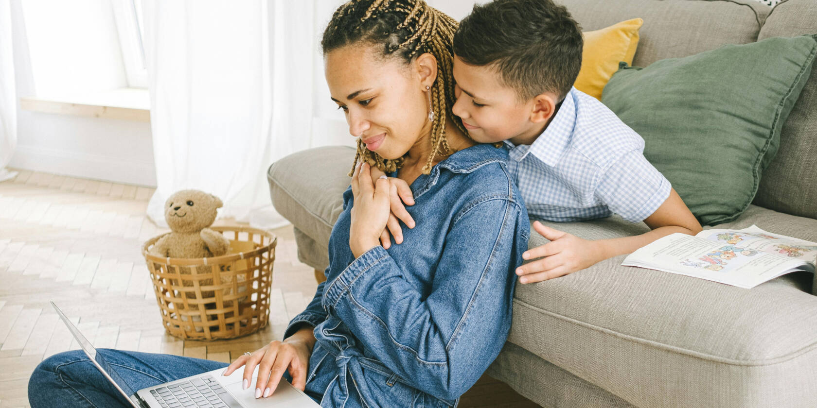 A woman and a child sit by a couch. The child holds his arm around the woman.