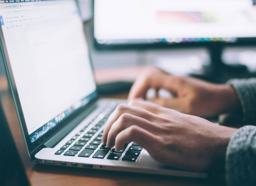 Hands typing on a laptop computer.