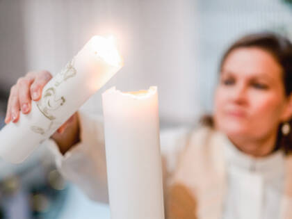 A pastor lights a baptism candle.