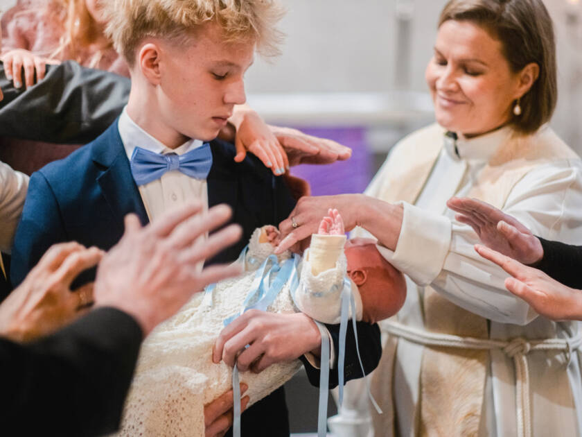 A priest is blessing a baby.