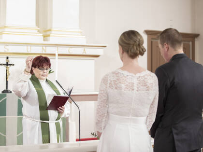 Pappi siunaa hääparia Tuomiokirkossa.