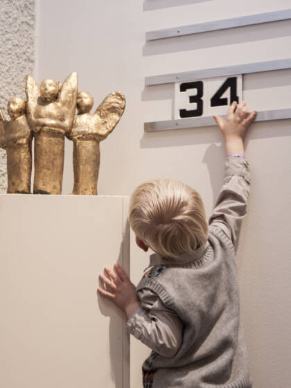Pieni lapsi kurottuu asettelemaan numeroita virsitauluun.