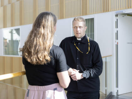 Pappi keskustelee sairaalan käytävällä.