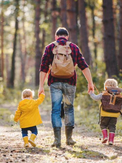A man and two children walking in the forest.