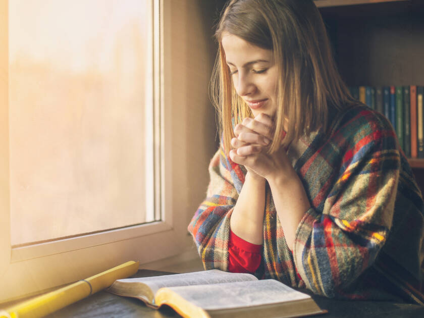 Woman praying having the Bible opened in front of she.