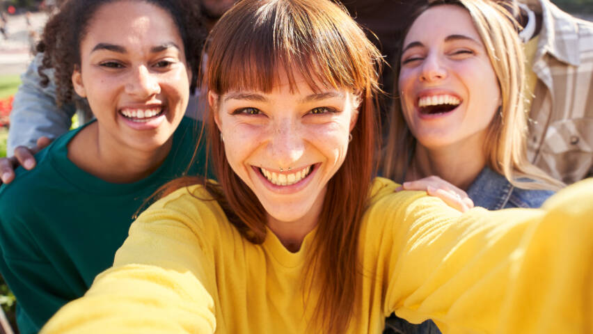 Joukko iloisia nuoria ottamassa selfietä porukasta.