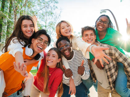 Big group of multiracial young student people smiling, gesturing and looking at camera.