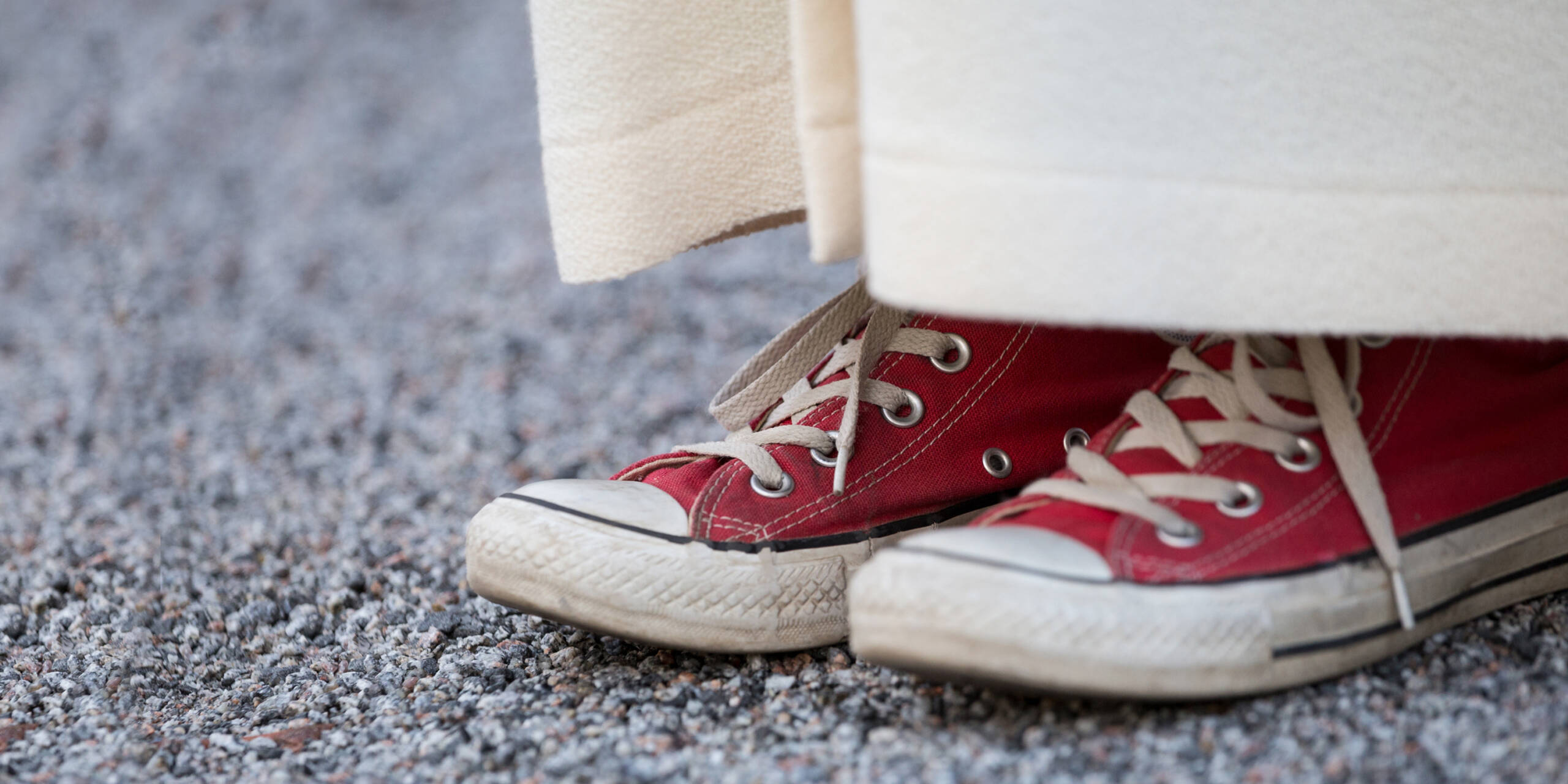 Nuori punaisissa Converse-tennareissa. Tennarit näkyvät alban alta lähikuvassa.