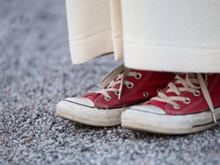 Nuori punaisissa Converse-tennareissa. Tennarit näkyvät alban alta lähikuvassa.