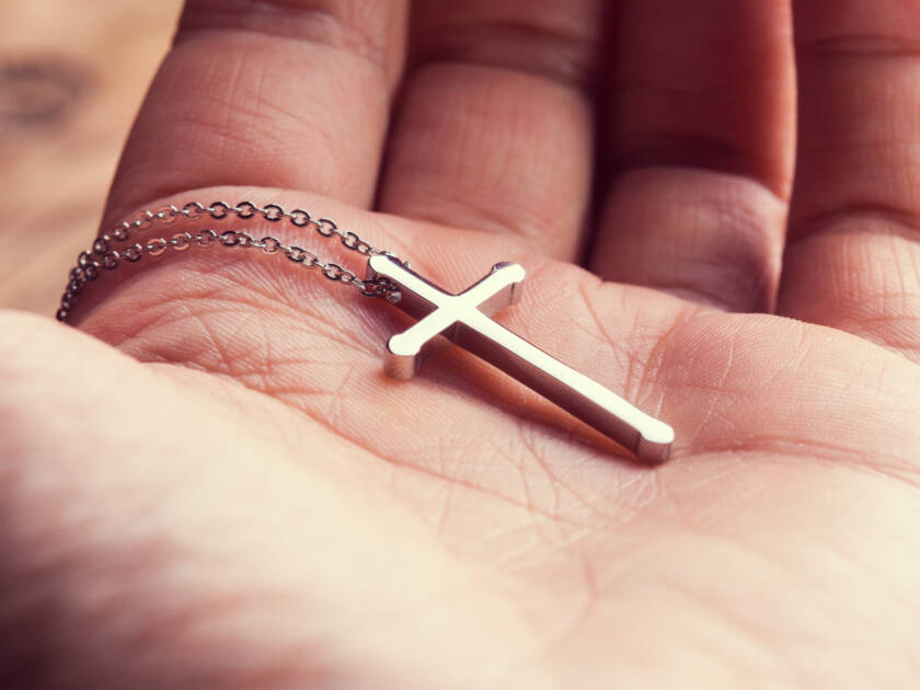 Silver cross in a hand close up image.