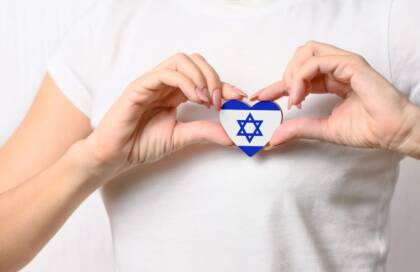 Israelin lipun näköinen kuva puusydämessä, jota pidetään käsillä kiinni.