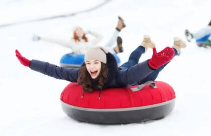 Nuoria henkilöitä laskemassa donitsilla mäkeä.