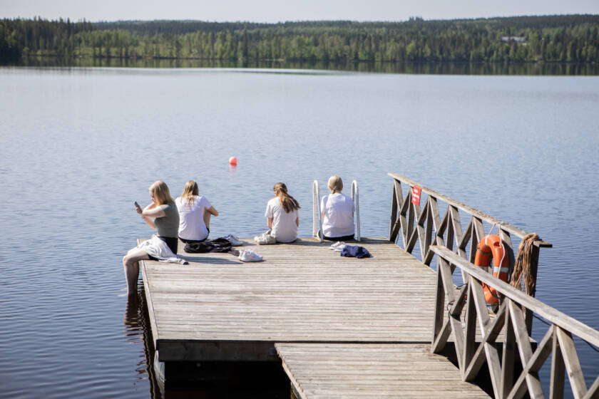 Rytkyn laituri kesäpäivänä ja sillä istumassa riparilaisia.