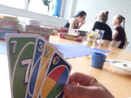 uno kortit ja taustalla 3 henkilöä juttelemassa.