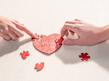 Hands assembling a heart-shaped puzzle
