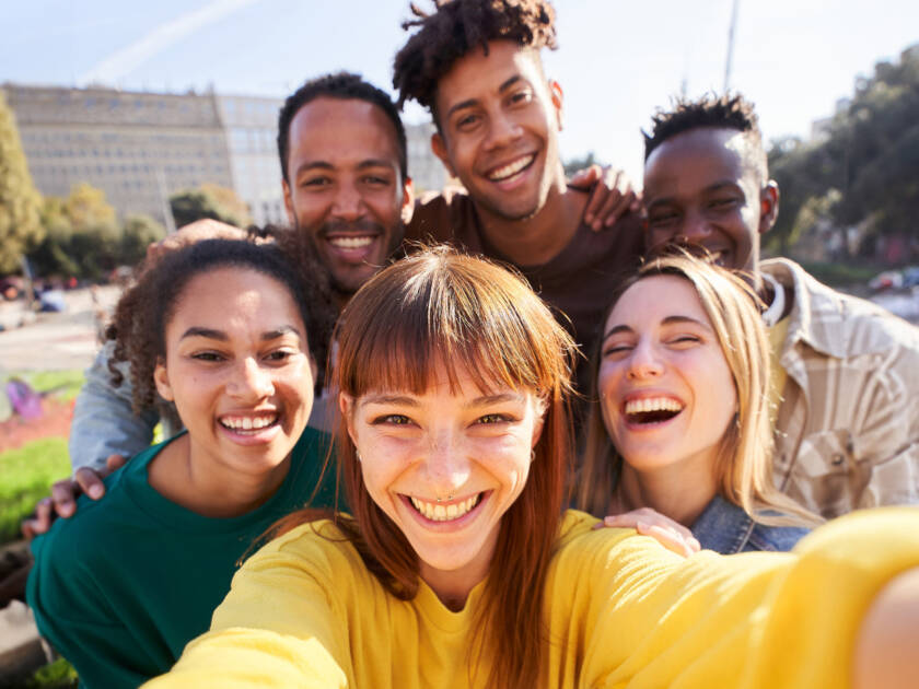 Group of happy friends posing for a selfie on a spring day as they party together outdoors.