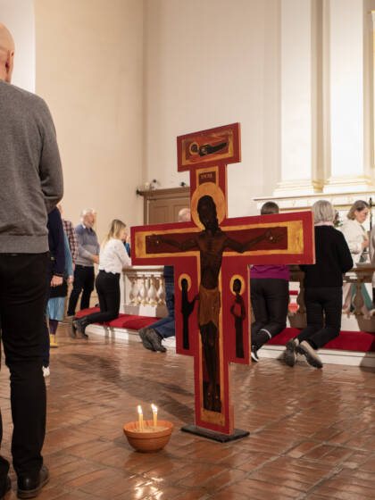 Alttarilla Taize-risti ja seurakuntalaisia menossa ehtoollista nauttimaan.