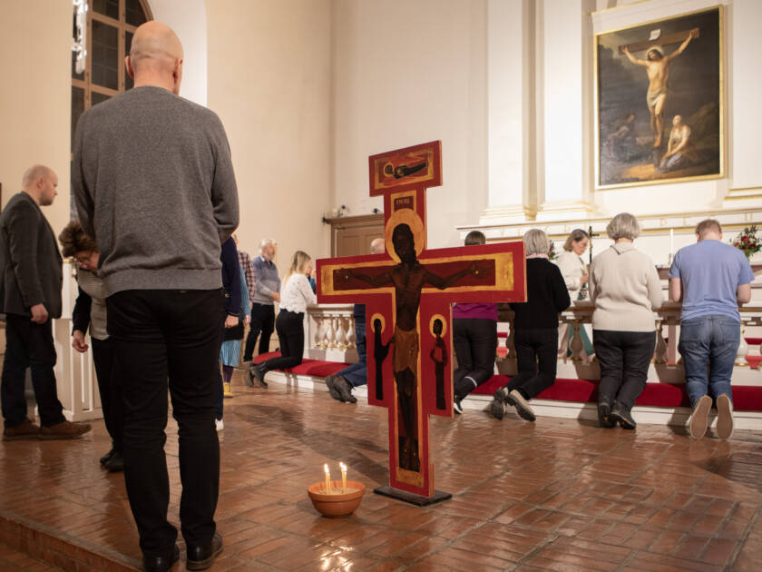 Alttarilla Taize-risti ja seurakuntalaisia menossa ehtoollista nauttimaan.