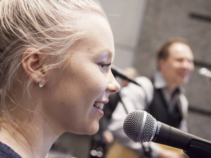 Kaksi henkilöä musisoimasssa, toinen laulaa mikrofoniin ja toinen soittaa kitaraa.