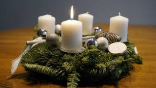 Neljä adventtikynttilää, joissa yhdessä liekki havu seppeleessä.
