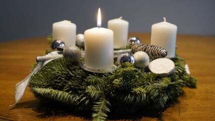 Neljä adventtikynttilää, joissa yhdessä liekki havu seppeleessä.