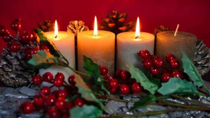 Neljä adventtikynttilää, joista kolmessa liekki puolukka oksa-käpyasetelmassa.