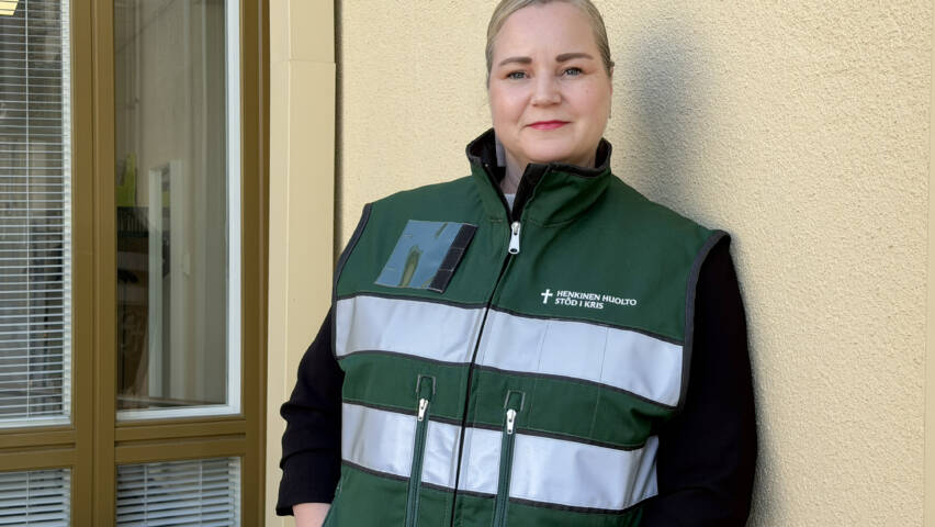 Nainen nojaa seinään HEHU-liivi päällään