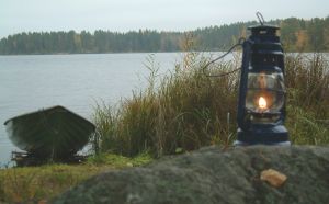 Vene rannalla, kiven päällä myrskylyhty, jossa valo.