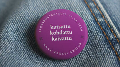 Farkkutakissa rintanappi, jossa seurakuntavaalien tunnus ja teksti "kutsuttu, kohdattu, kaivattu"