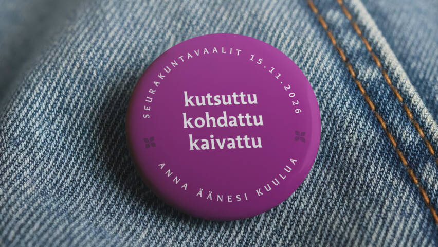 Farkkutakissa rintanappi, jossa seurakuntavaalien tunnus ja teksti "kutsuttu, kohdattu, kaivattu"