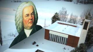 Bach-säveltäjän kuva ja Puijon kirkkorakennus katolta katsottuna.